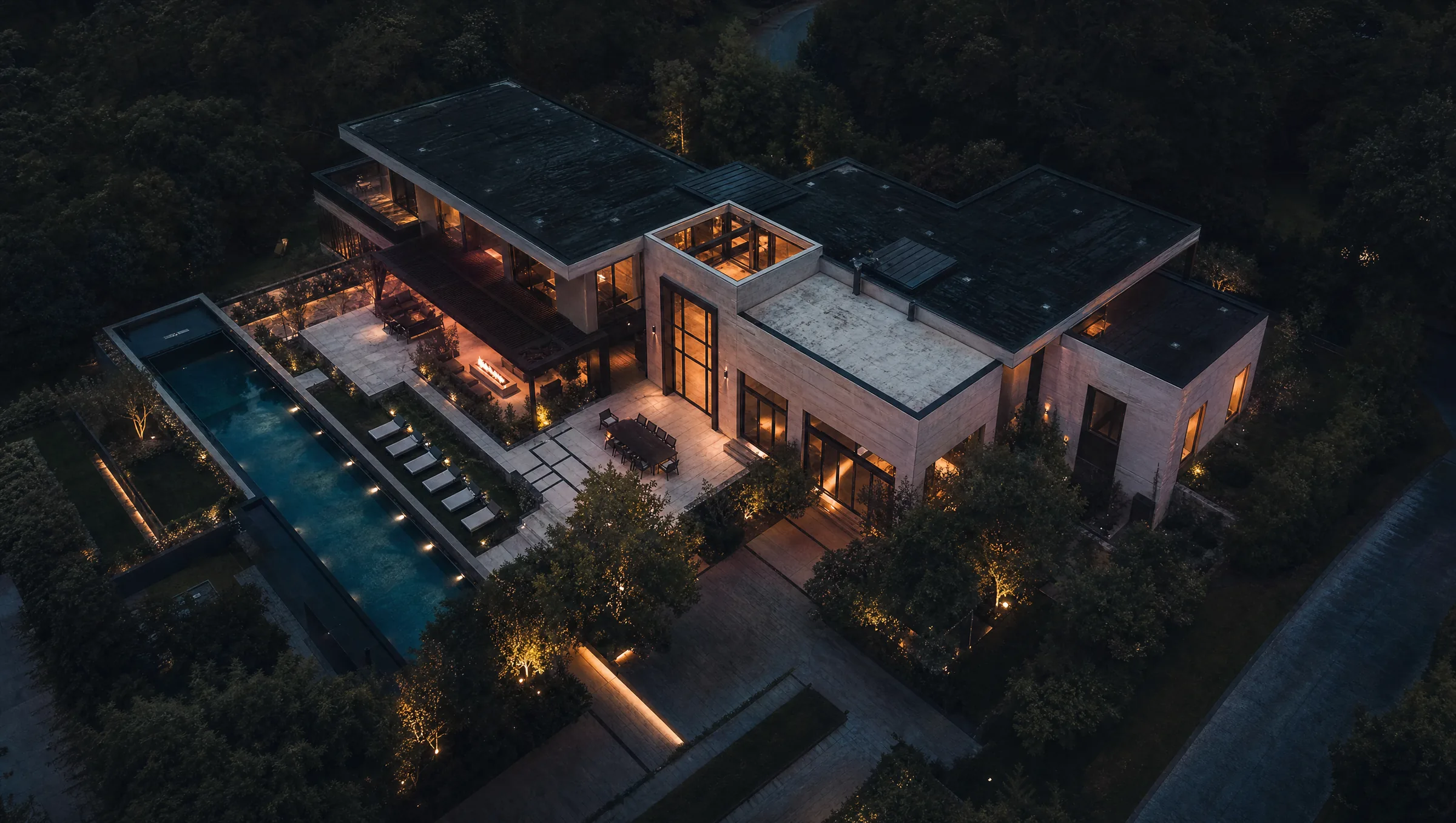 Aerial view at dusk of a modern home with a pool and landscaped grounds